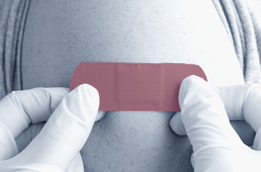 A red plaster is stuck on a man's upper arm with two hands 